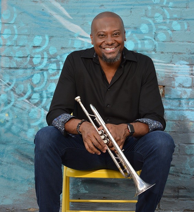 Sean Jones sitting in a chair holding his trumpet