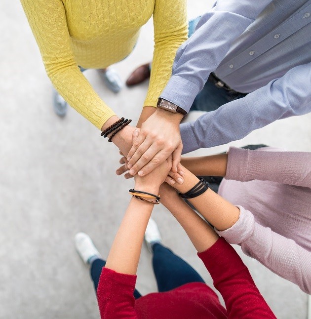 four people in a huddle with their hands on top of each other
