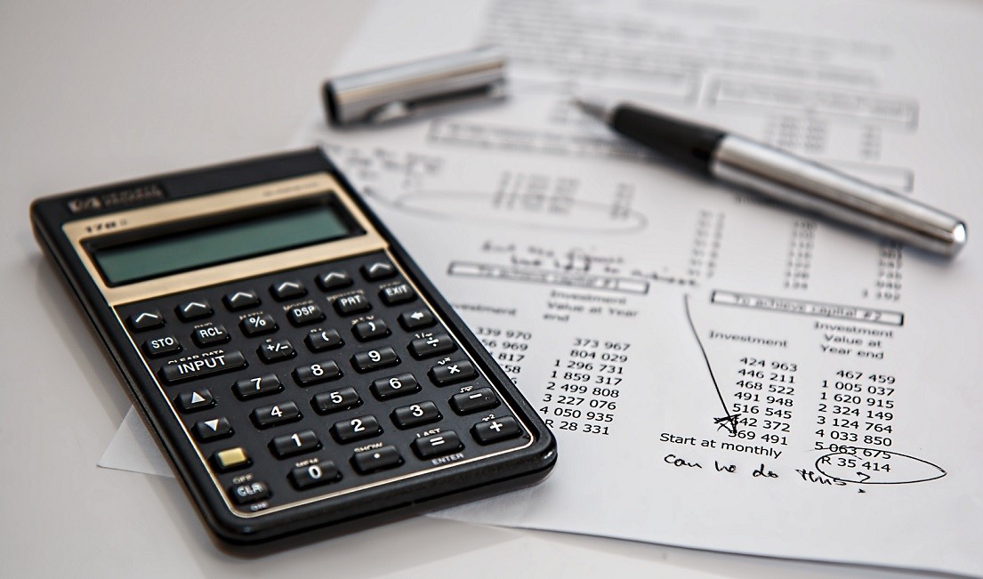 calculator and pen on top of budget paperwork