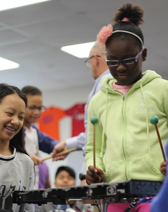 United Sound peer mentor watches as a new musician plays a mallet instrument