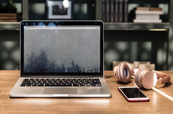 desk with open laptop, smartphone and earphones