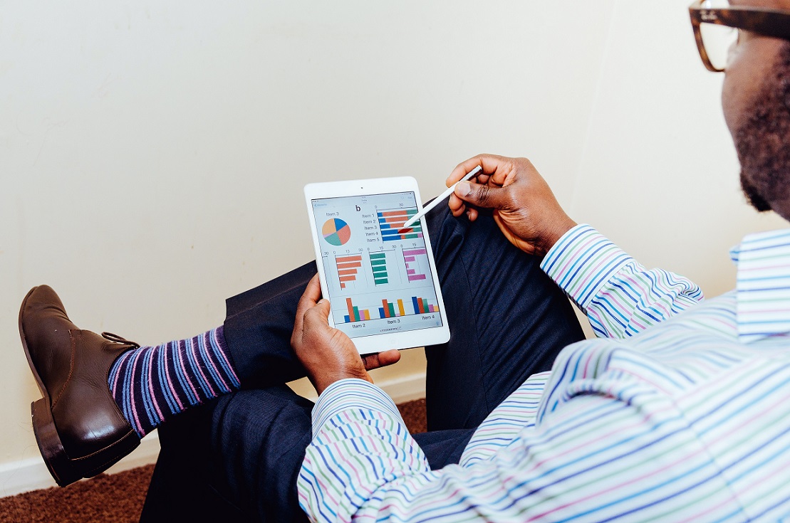 male looking at tablet with various bar and pie charts