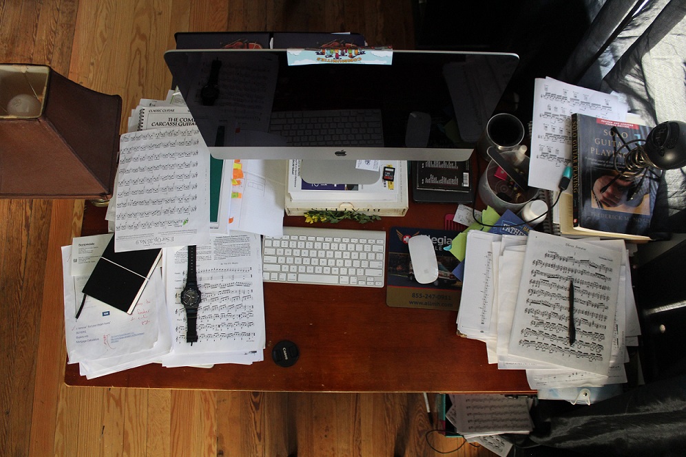 view of a desk from above with computer monitor and stacks of papers