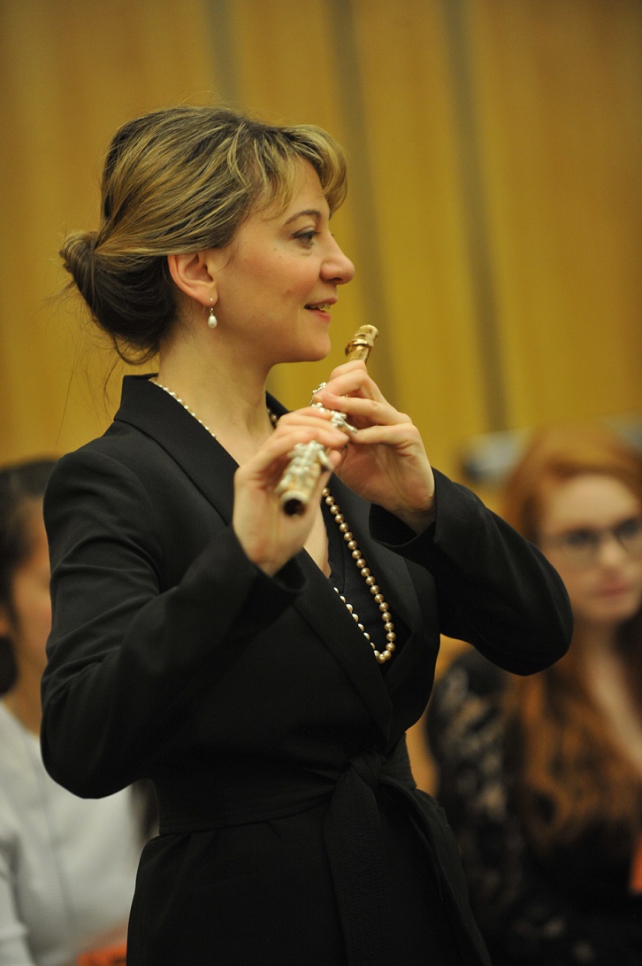 Mimi Stillman holding flute in front of a group of students