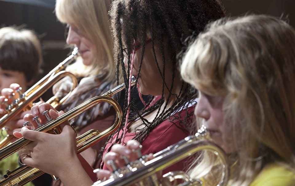 three students playing the trumpet