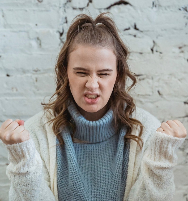 frustrated woman with grimace on her face and fists held up