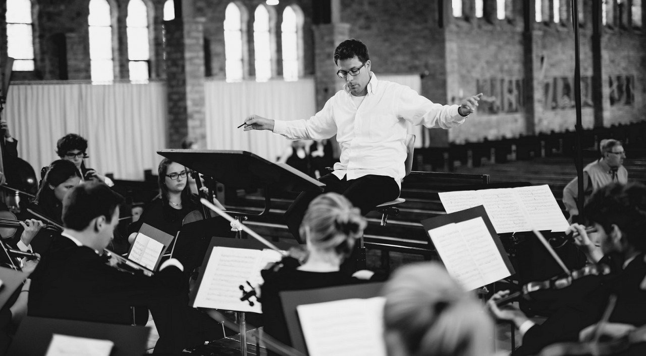 male music educator conducting in front of band 