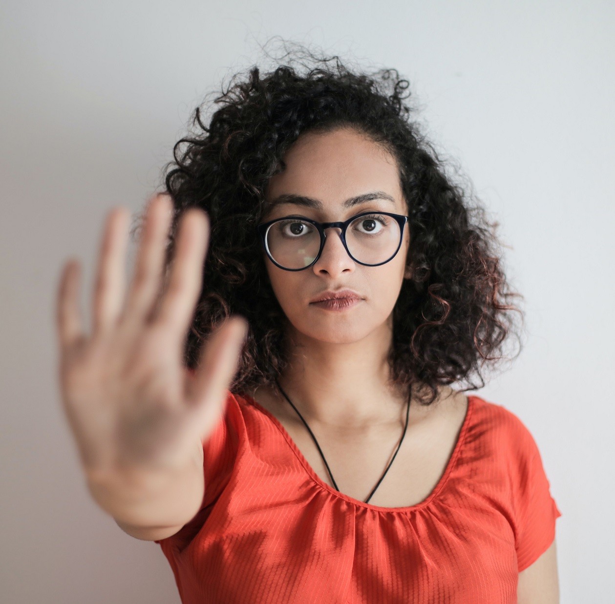 woman with serious look on face and open hand held out in front of her as if to say stop