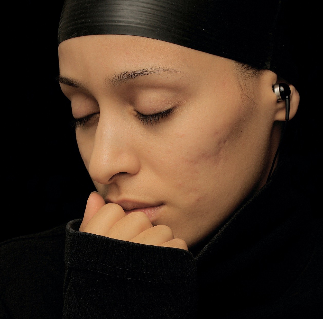 woman with eyes closed, listening to music through earbuds