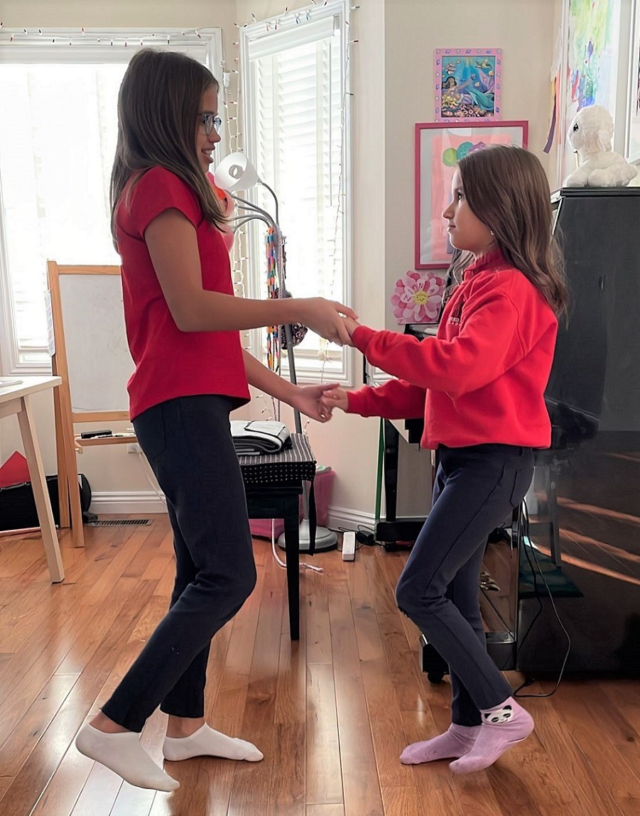 two female students facing each other while holding hands and swaying 