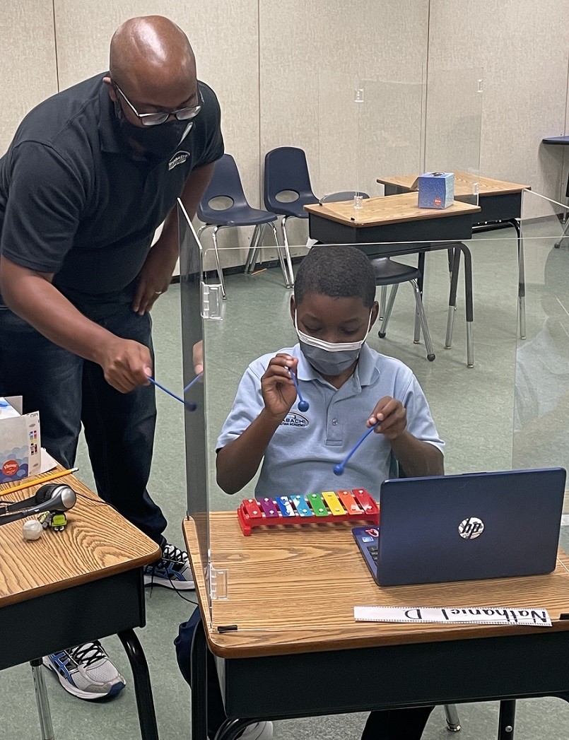 Brandon Felder oversees student playing small xylophone