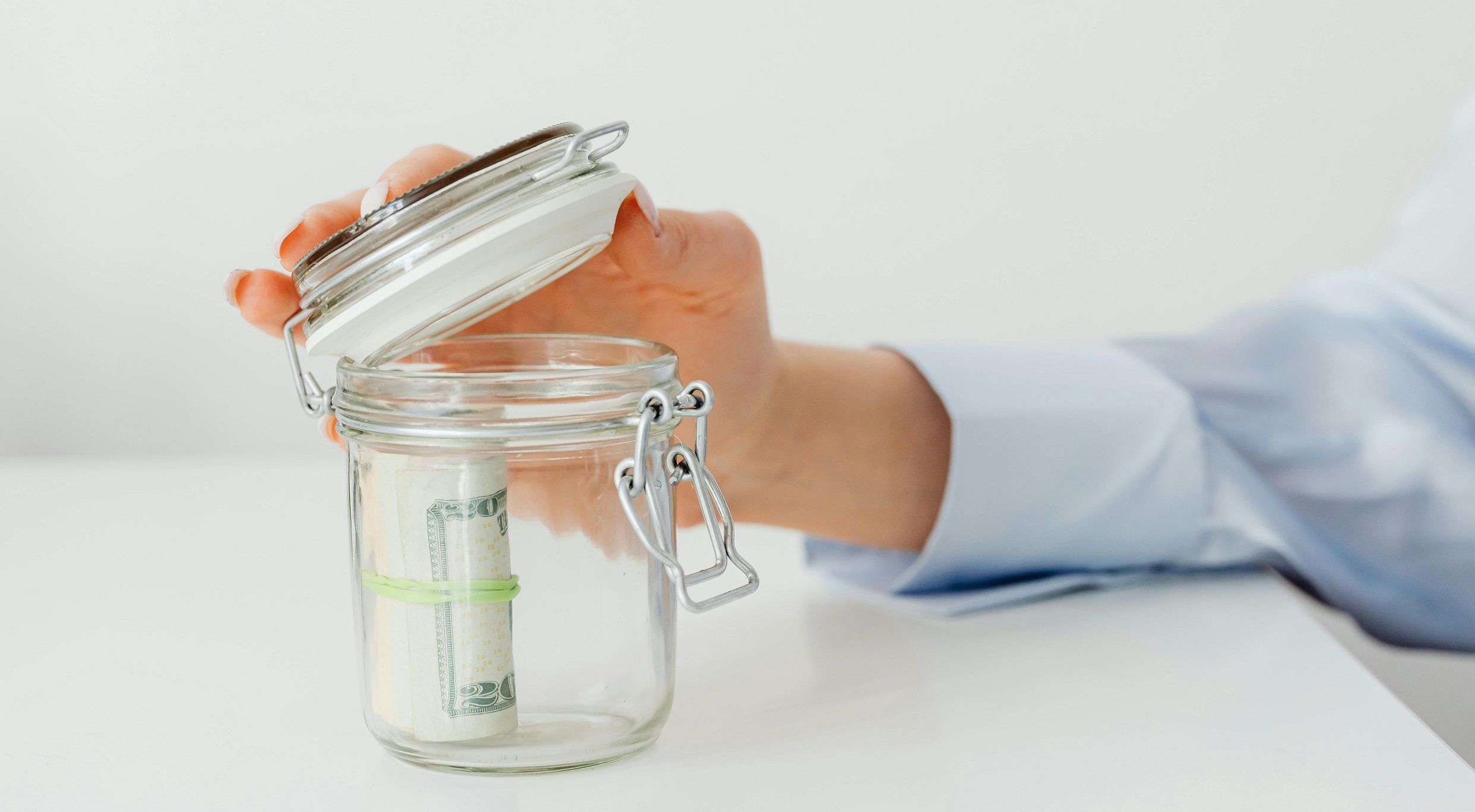 hand closing a jar with money in it