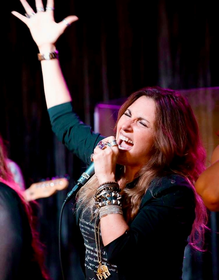 A female singer with her hand raised in the air.