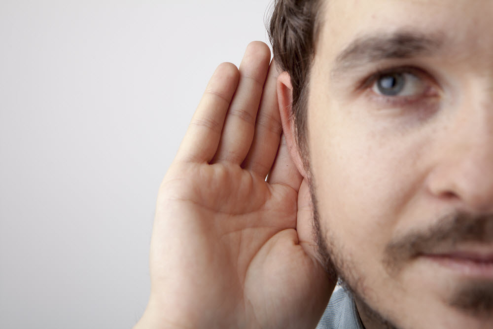 Man with a hand up to his ear.