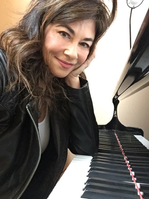 shelly waiting for inspiration Smiling woman leaning on her elbow on the keys of a piano.