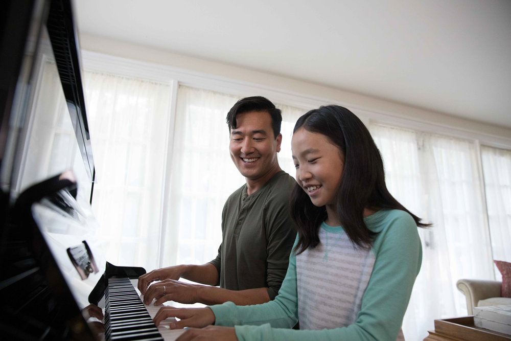 Yamaha fatheranddaughteratpiano Young girl and her father play piano together.