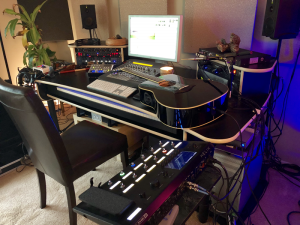 Acoustic guitar on desk next to laptop.