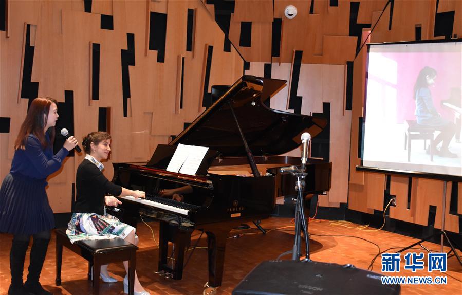 Pianos without borders body image 3 An image of a person playing a piano while someone stands behind her with a microphone.