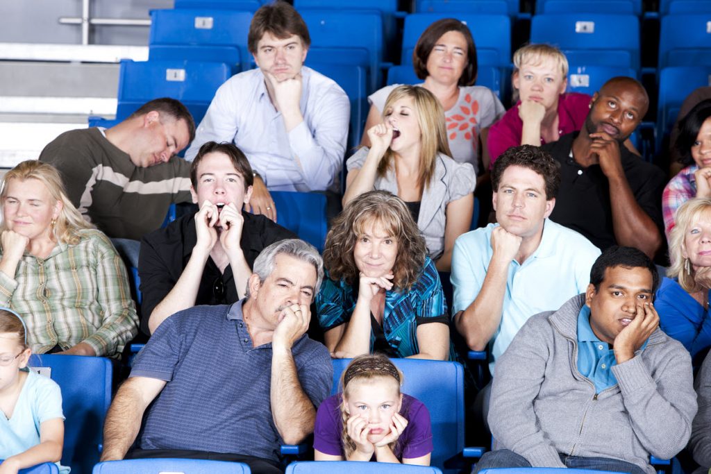 may editors corner body feature image A group of people in stadium seats yawning, sleeping resting heads on hands with expressions of boredom.