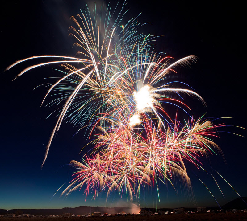 Fireworks exploding in night sky over a town.