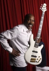 nathan east with yamaha bbne2 bass Smiling man with hand on hip holding a bass guitar.