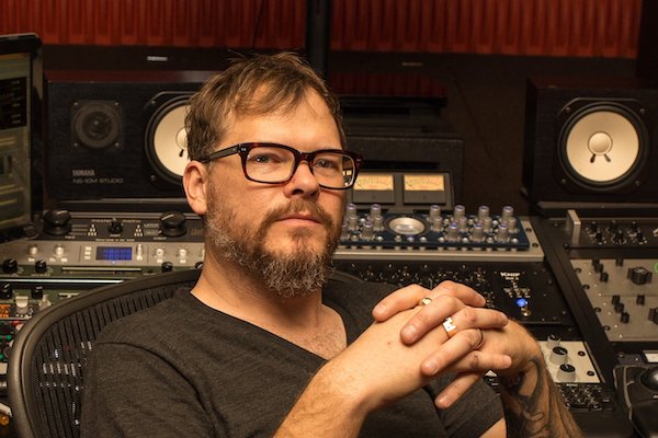 Mastering engineer in studio sitting in front of mixing console.