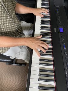 JK_Practice Man in button-down shirt and cargo pants practices on an electric keyboard.