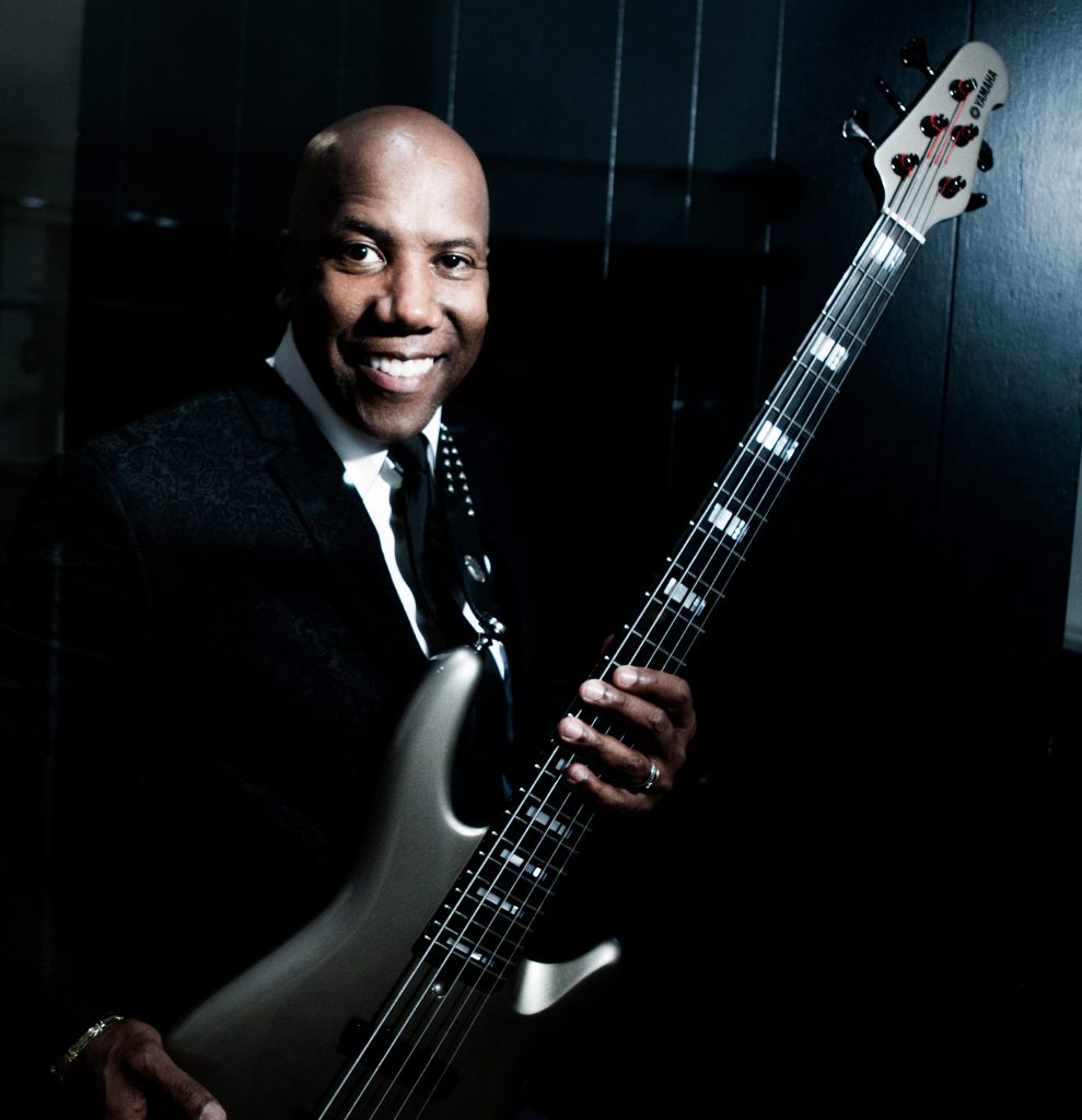 Nathan East smiling while holding his signature Yamaha bass.