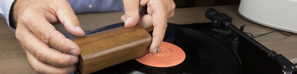 Man using using an anti-static cleaning brush to clean vinyl record.