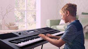Child playing portable keyboard and smiling.