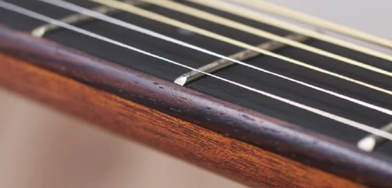 FIG-7-A5-Neck-taper Close up of a guitar neck with strings.
