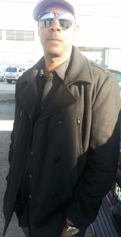 DeVon-Manier-1 Man in coat, cap and sunglasses faces the camera.