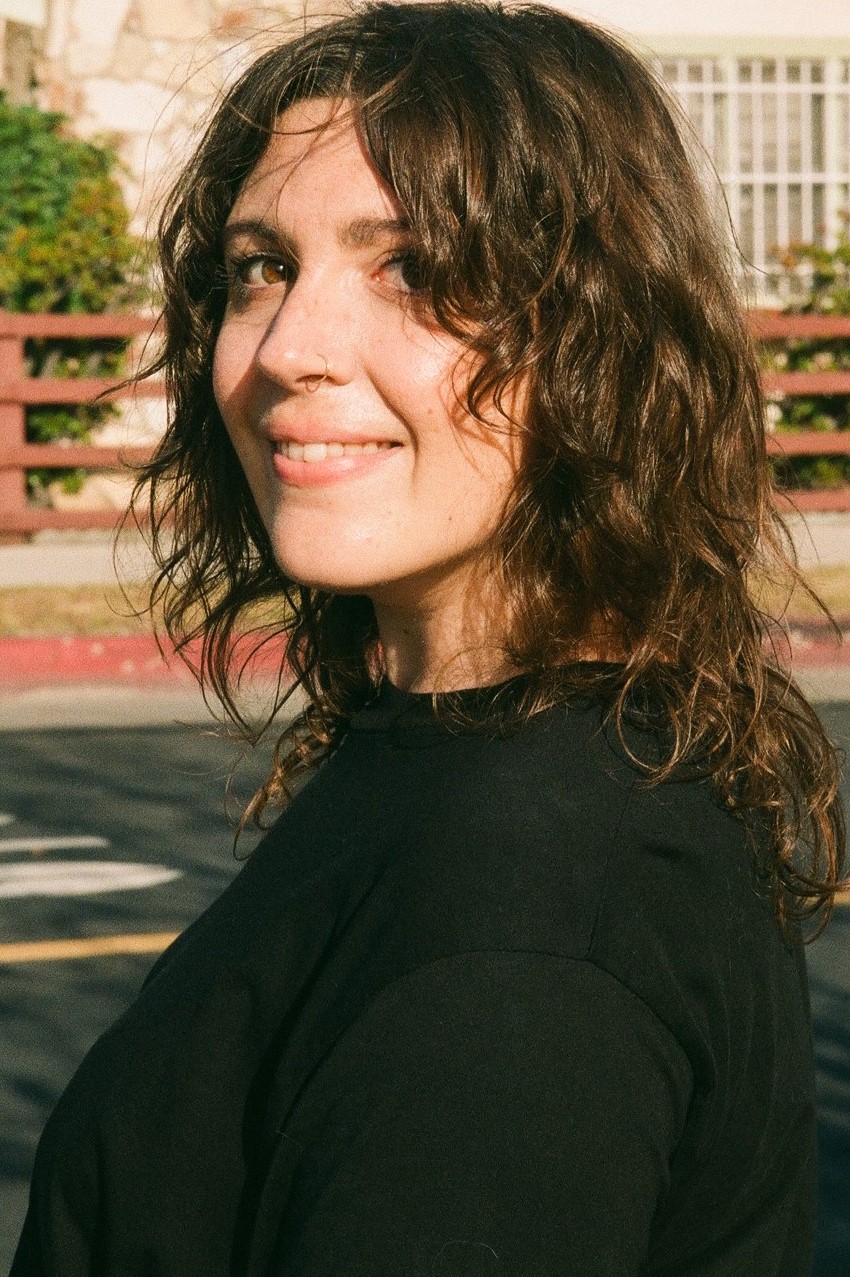 Shayna-Casey-1 Young woman looking over her shoulder smiling at camera.