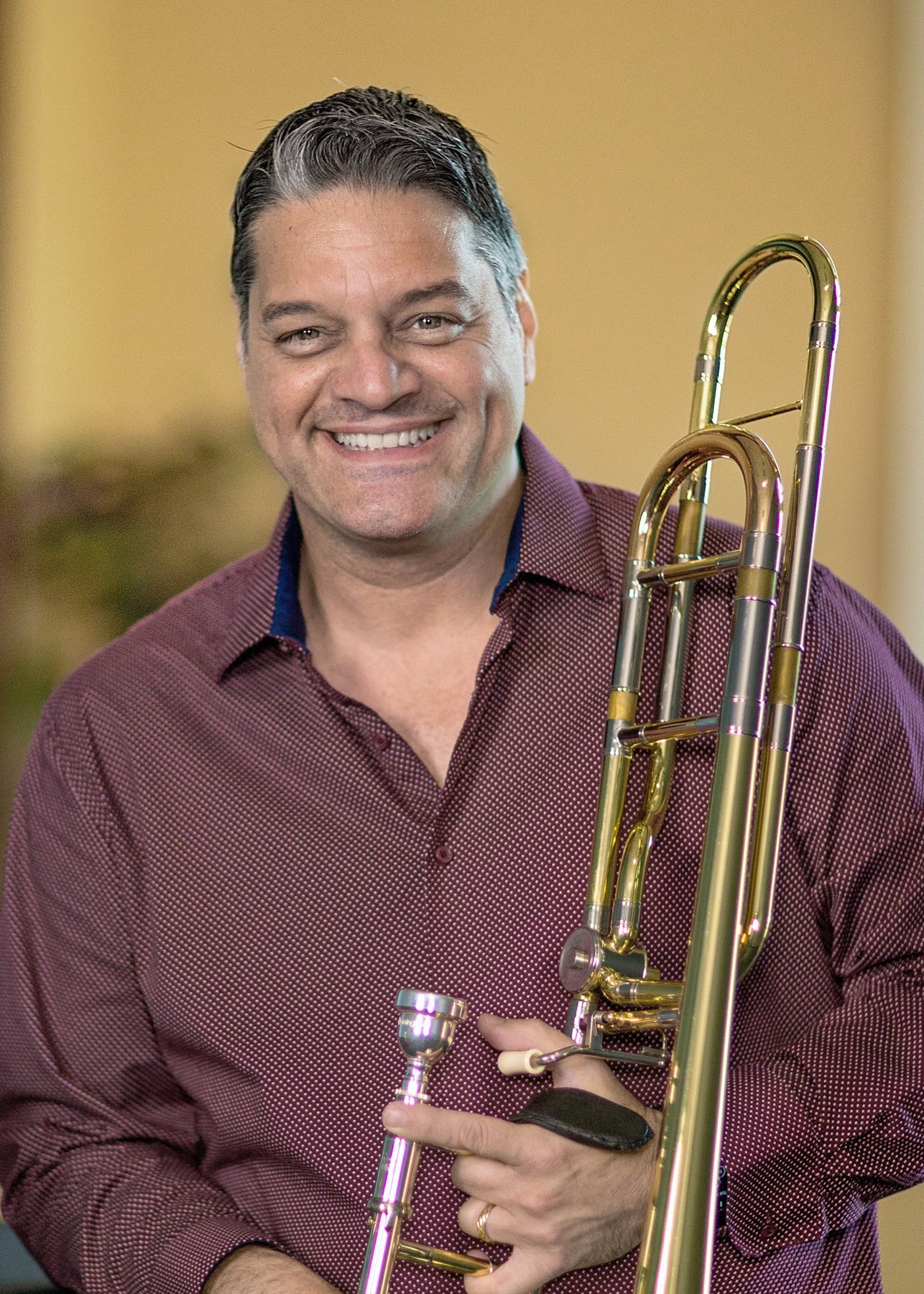 Domingo-Pagliuca Headshot of smiling man holding a trombone.