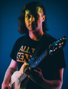 Photo of a man holding a guitar.