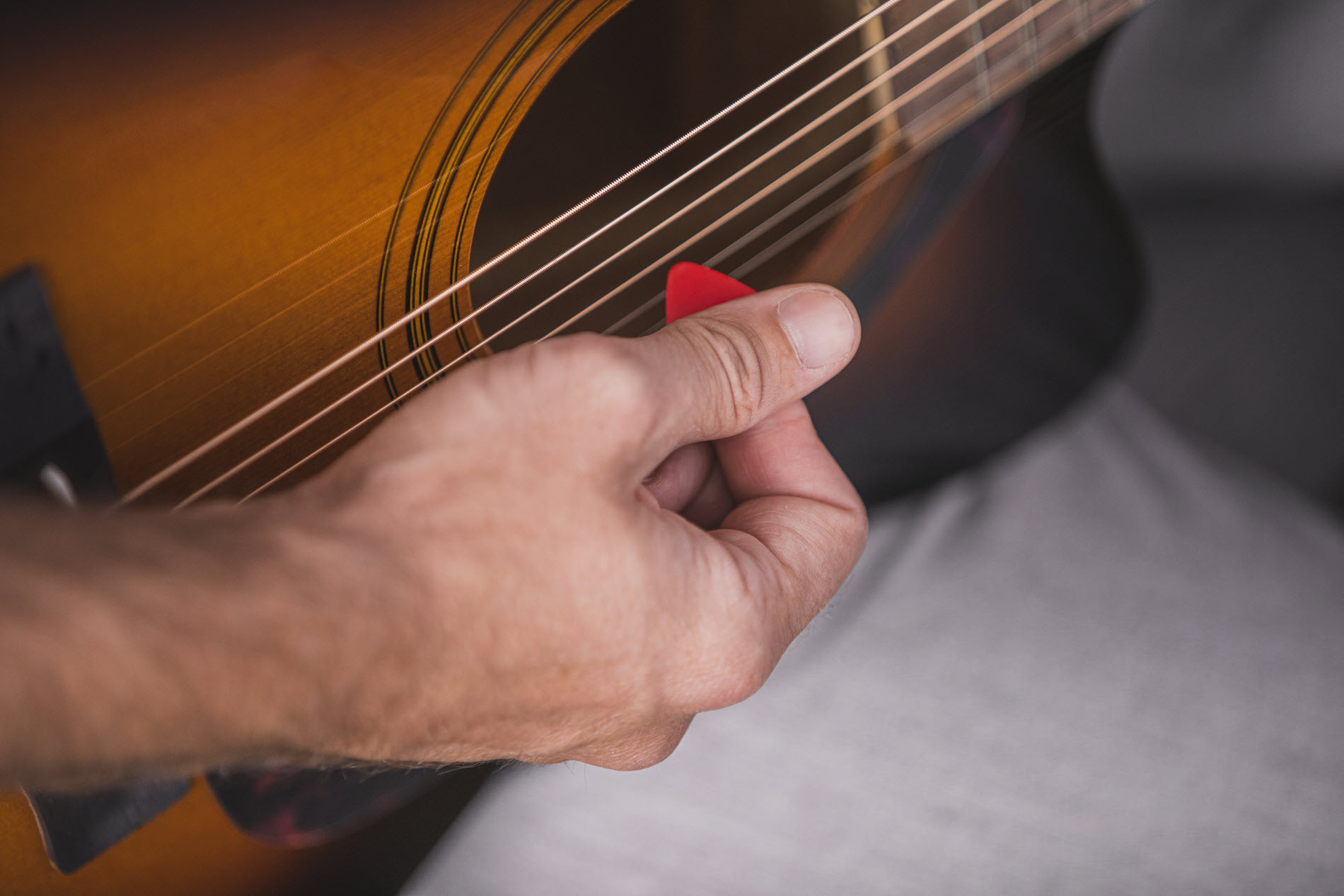 guitartips5 Closeup of someone picking guitar strings on acoustic guitar.