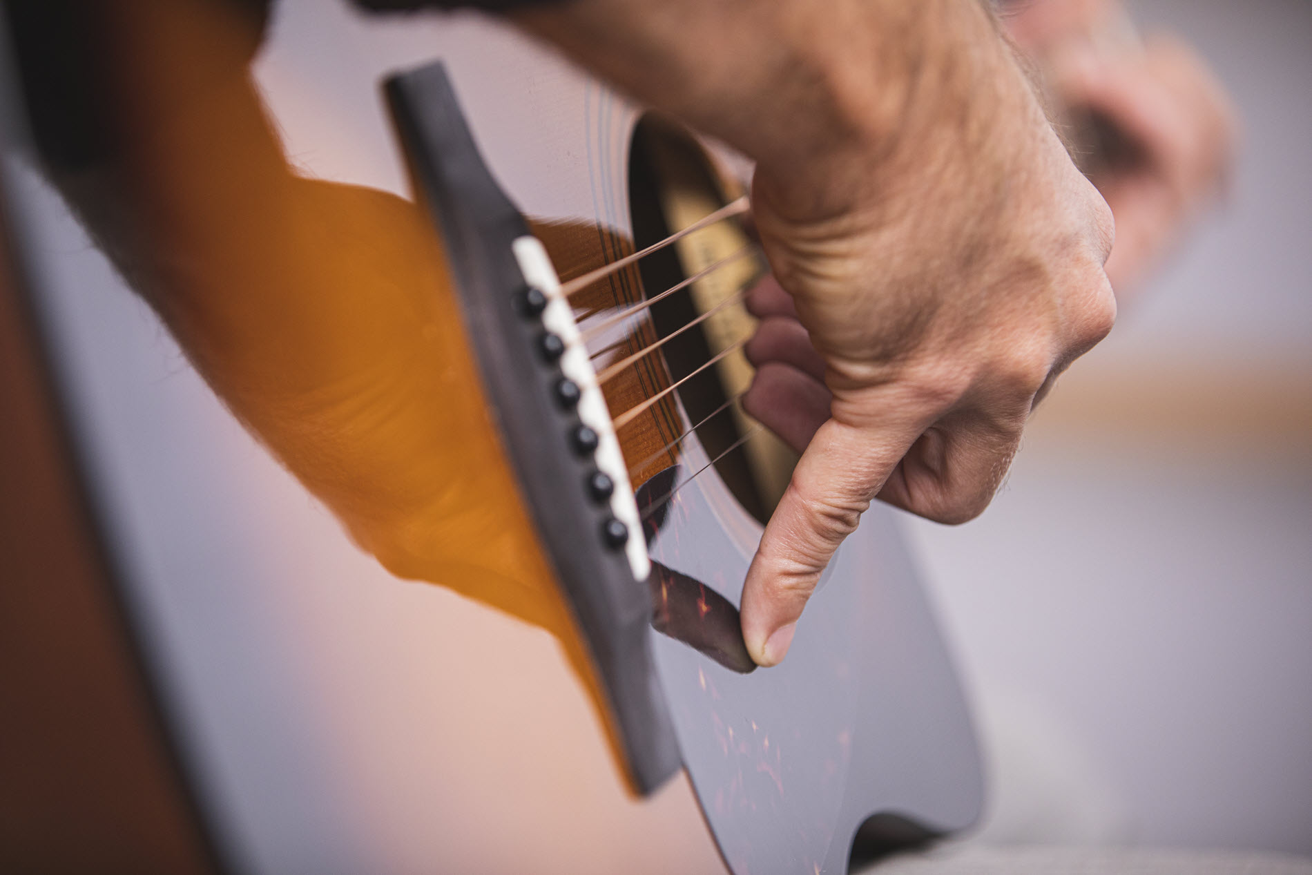 guitartips9 Closeup of someone's hand as they play acoustic guitar.