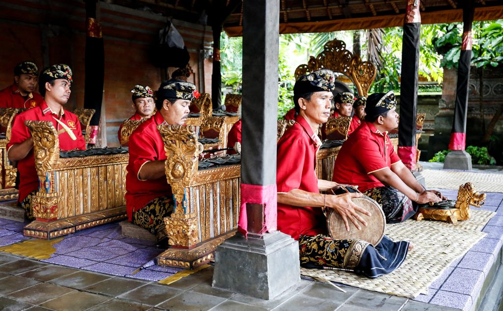 Gamelan Group of men in traditional dress playing instruments in a pavilion.