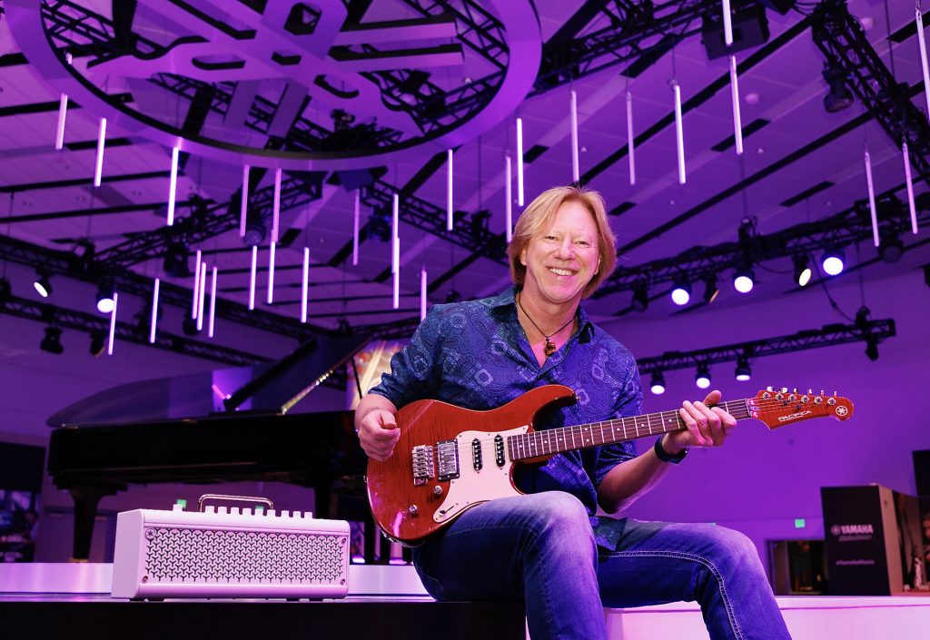 Robbie Calvo holding a guitar and smiling for camera.