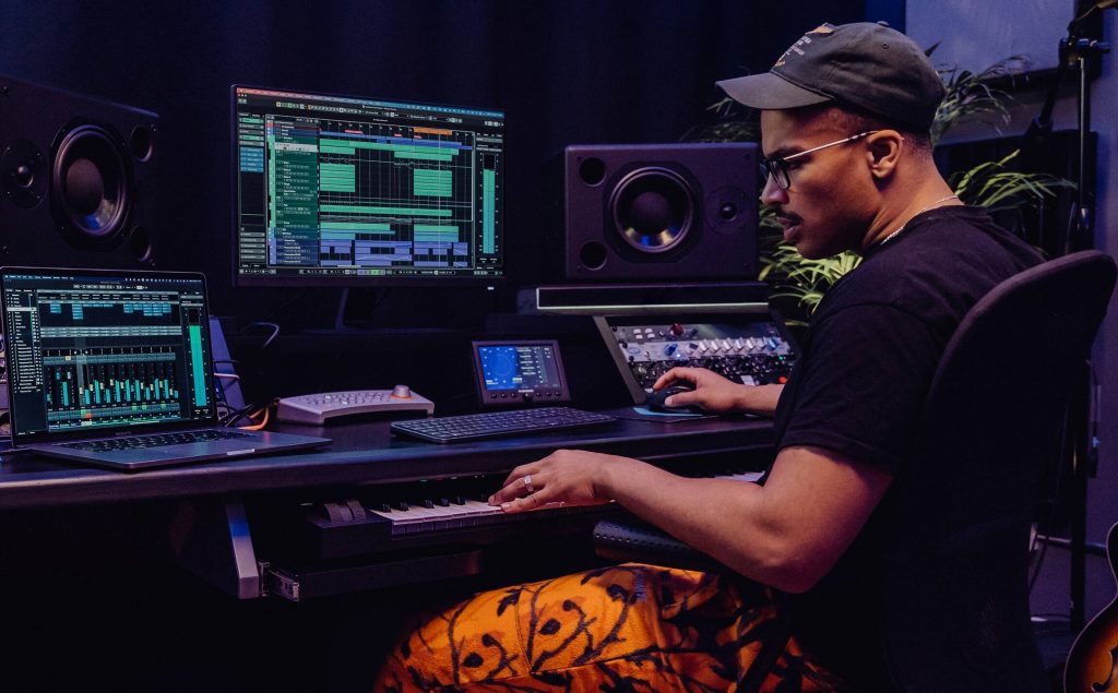 A sound engineer at the keyboard with array of technology tools on screen in front of him.