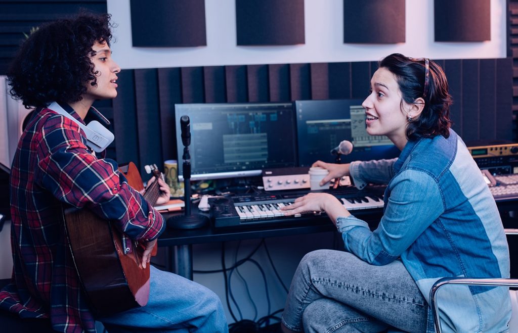 Two young women at the editing desk of a sound studio in discussion.