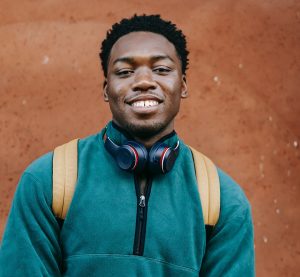 happy male student with headphones around his neck