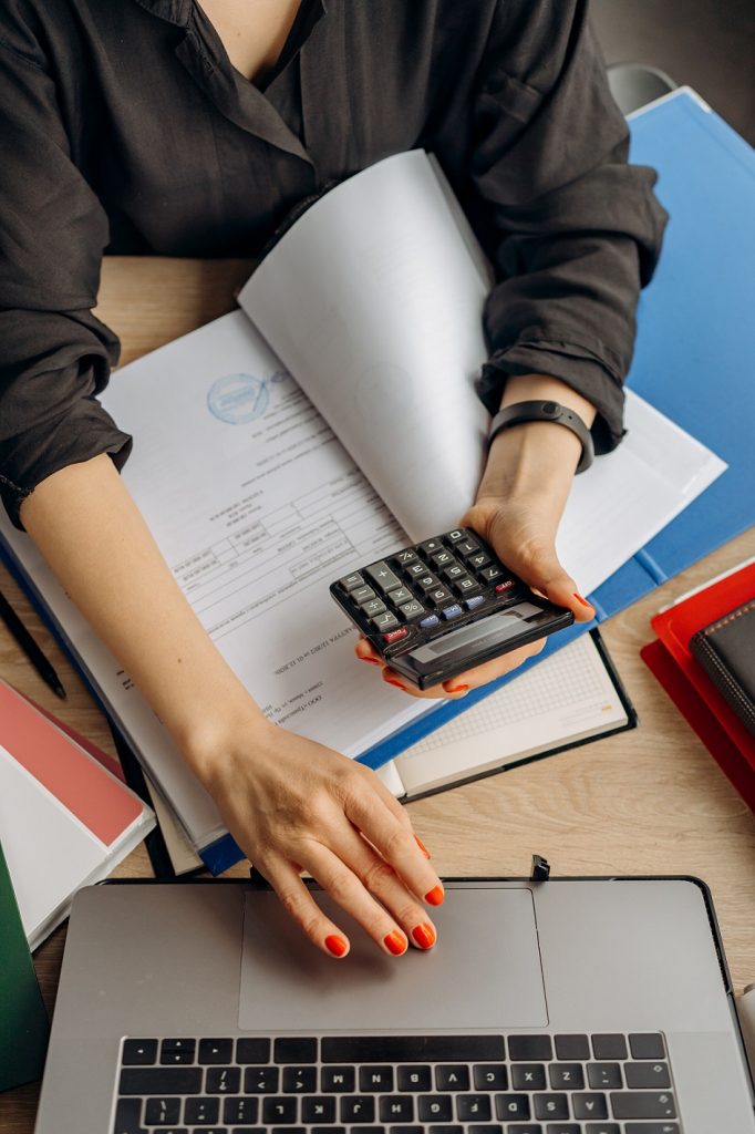 female working on laptop while holding a calculator