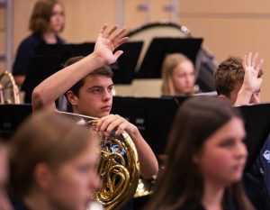 brass section rehearsal with student raising his hand