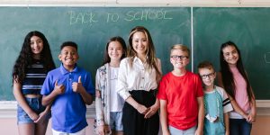 teacher standing with a group of students in front of blackboard