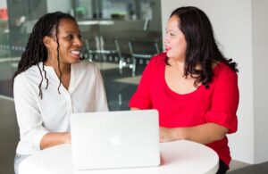 two women talking while sitting at a table