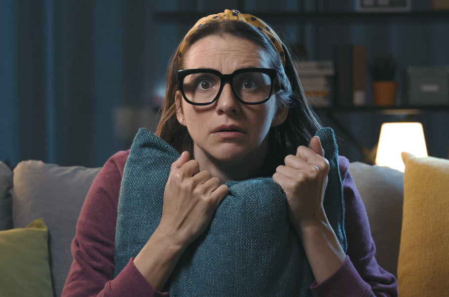 Woman clutching a pillow with a scared expression.