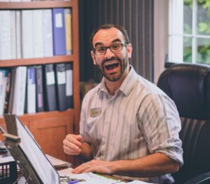 excited male teacher sitting at desk