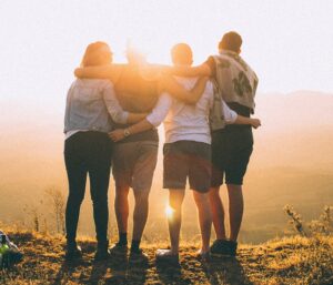 group of four students with arms clasp and looking out onto a sunset