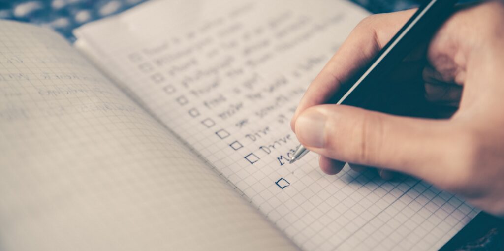 close up of hand writing down checklist of tasks